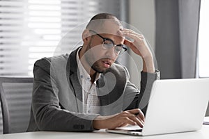 Thoughtful businessman using laptop pondering over problem solving