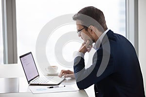 Thoughtful businessman writing business email on laptop