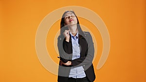 Thoughtful businesswoman posing over orange backdrop