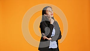 Thoughtful businesswoman posing over orange backdrop