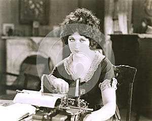 Thoughtful businesswoman with typewriter at desk in office