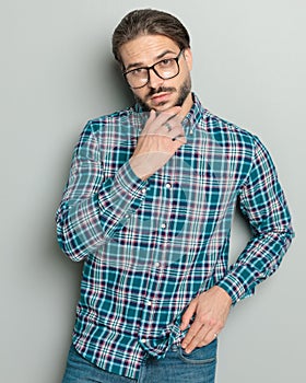 thoughtful casual man in shirt with glasses touching chin and thinking