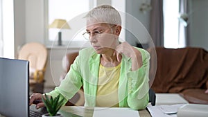 Thoughtful Caucasian middle aged businesswoman surfing internet on laptop sitting indoors planning strategy. Portrait of