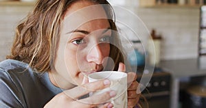 Thoughtful caucasian woman in sunny cottage kitchen drinking coffee