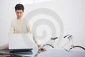 Thoughtful causal businessman using laptop