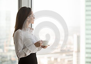 Thoughtful ceo enjoying view from window drinking coffee