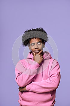 Thoughtful confused African teen guy thinking isolated on purple. Vertical
