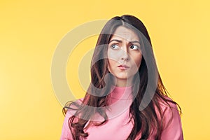 Thoughtful confused woman looking away isolated over yellow background