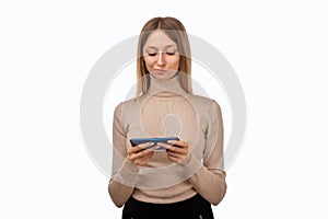 Thoughtful confused young blond woman holding her smart phone. Technology, youth and communication concept