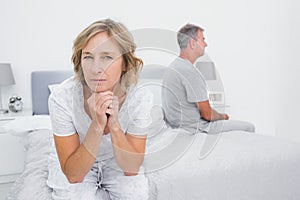 Thoughtful couple sitting on different sides of bed having a dis