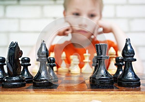 Thoughtful cute boy playing checkmate