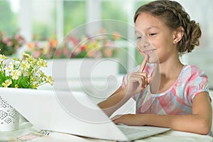 Thoughtful cute girl using laptop at home