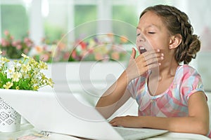 Thoughtful cute girl using laptop at home