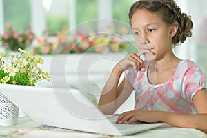 Thoughtful cute girl using laptop at home