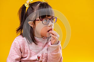 Thoughtful dark-haired child with abnormality eating snacks