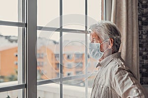 Thoughtful depressed old man looking out of window with hope, thinking over business lockdown loss, future vision after epidemic