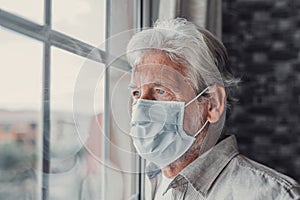 Thoughtful depressed old man looking out of window with hope, thinking over business lockdown loss, future vision after epidemic