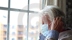 Thoughtful depressed old man looking out of window with hope, thinking over business lockdown loss, future vision after epidemic