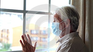 Thoughtful depressed old man looking out of window with hope, thinking over business lockdown loss, future vision after epidemic