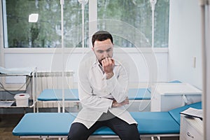 Thoughtful doctor sitting in a operating room with his hand on head