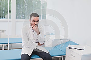 Thoughtful doctor sitting in a operating room with his hand on head