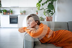 Thoughtful dreaming woman lying on sofa looking aside window enjoy calmness for tranquil relaxation.