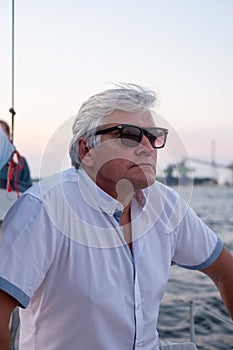 Thoughtful elderly man on a yacht at sunset, the ocean backdrop providing a contemplative atmosphere, perfect for themes