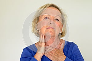 Thoughtful elderly woman with her hand to her neck