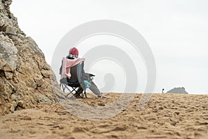 Thoughtful elderly woman sitting touristic chair on sea beach looking horizon Loneliness and old age concept