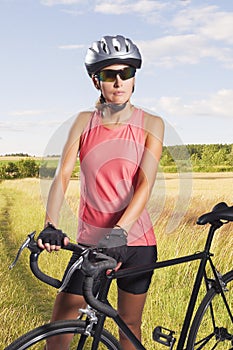 Thoughtful female biker hodling a bike. athlete equipped with pr