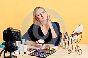 Thoughtful female makeup artist applying face cream, focused expression