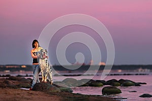 Thoughtful female owner with dog on coastline