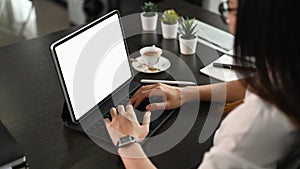 Thoughtful female person looking to digital tablet screen while sitting in office.