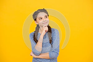 Thoughtful girl with braids. adorable daydreaming kid. think about future. Portrait of pensive teen girl on yellow