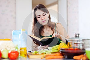 Thoughtful girl cooking with cookbook