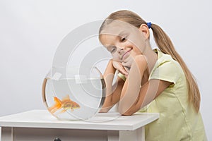 Thoughtful girl dreaming and looking at goldfish