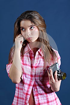 Thoughtful girl holds old camera and looks up