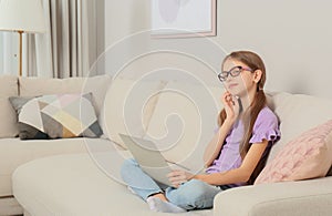 Thoughtful girl with laptop on sofa