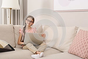 Thoughtful girl with laptop on sofa at home