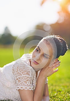 Thoughtful girl laying on grass