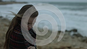 Thoughtful girl looks at the sea in the winter in windy weather