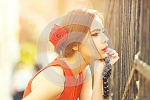 Thoughtful girl with red roses in hair and black beads