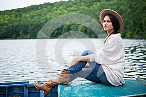 Thoughtful girl sits in a boat on a lake