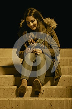 Thoughtful girl sitting on a stairs and looking her hands