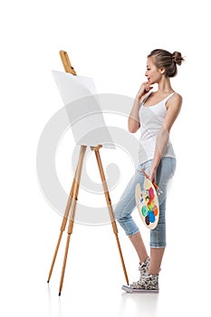 Thoughtful girl standing by canvas.