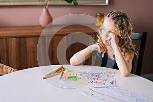 Thoughtful girl thinking about what picture do drawing with colorful pencil at the table i