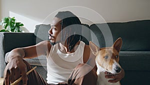 Thoughtful guy embracing dog at sofa room closeup. Artist relaxing after drawing