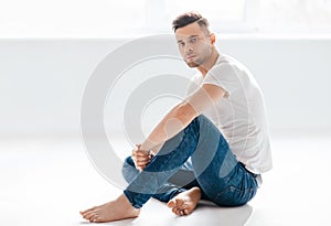 Thoughtful handsome man portrait sitting on floor