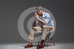 Thoughtful handsome young man sitting on chair and looking away