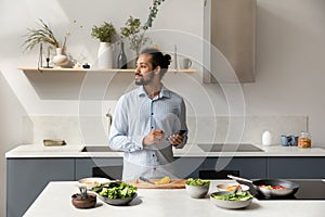 Thoughtful hipster guy consulting cooking online recipe on internet